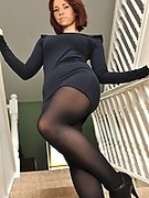 British girl in a black dress, pantyhose and high heels strips on the stairs
